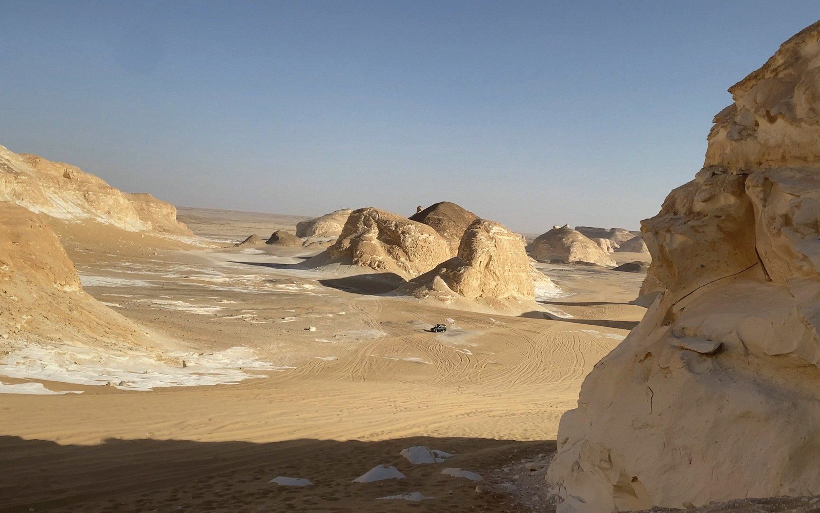 A desert escarpment rising above rolling dunes